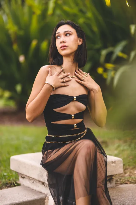 A woman wearing a black dress in a green garden.