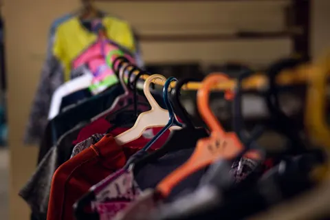 Colorful garments hanging on a rail inside a clothing shop.