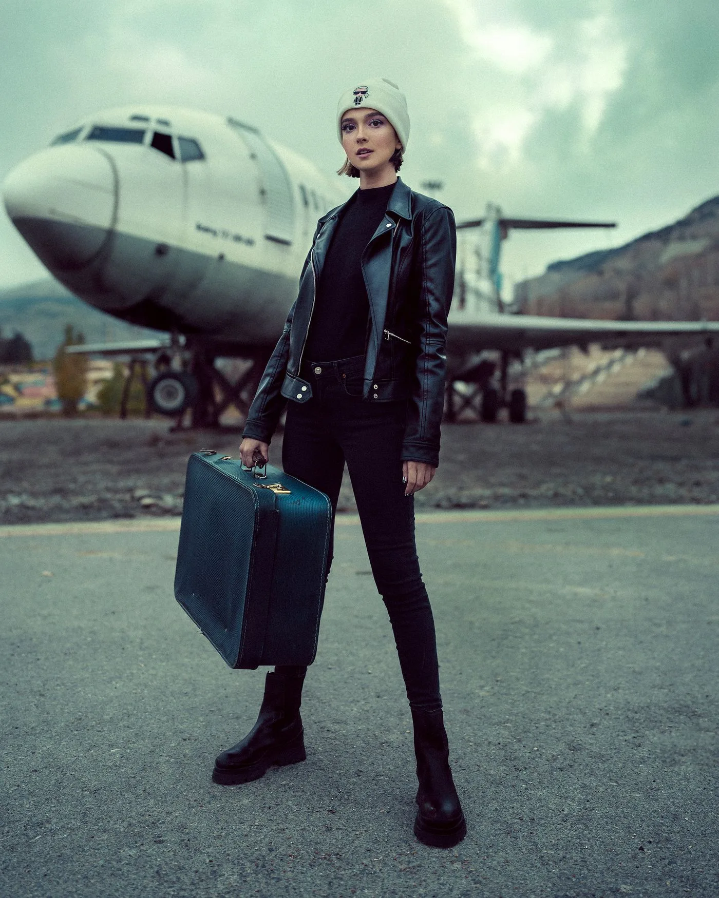 A woman holding a suitcase near an airplane