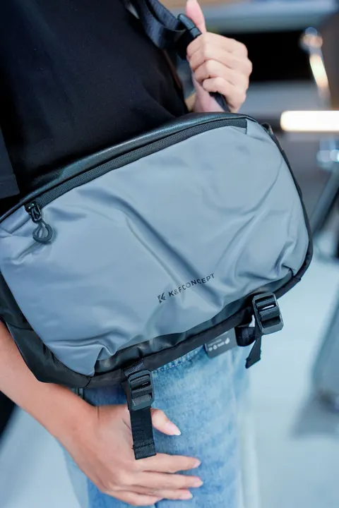 A close view of a crossbody bag worn over casual clothing.