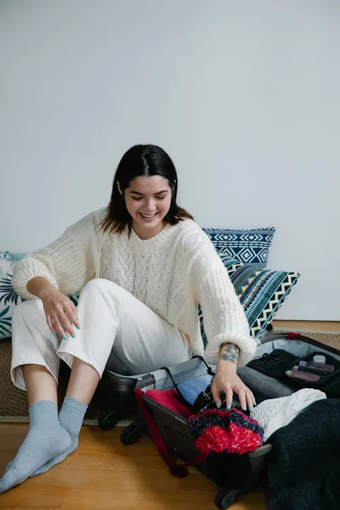 A woman packing a suitcase on the floor at home.