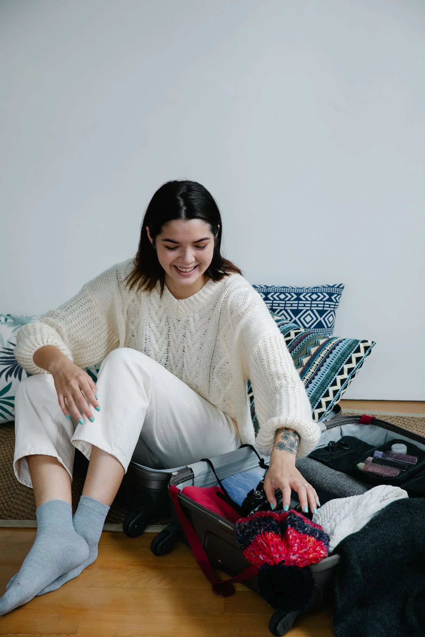 A woman packing a suitcase on the floor at home.